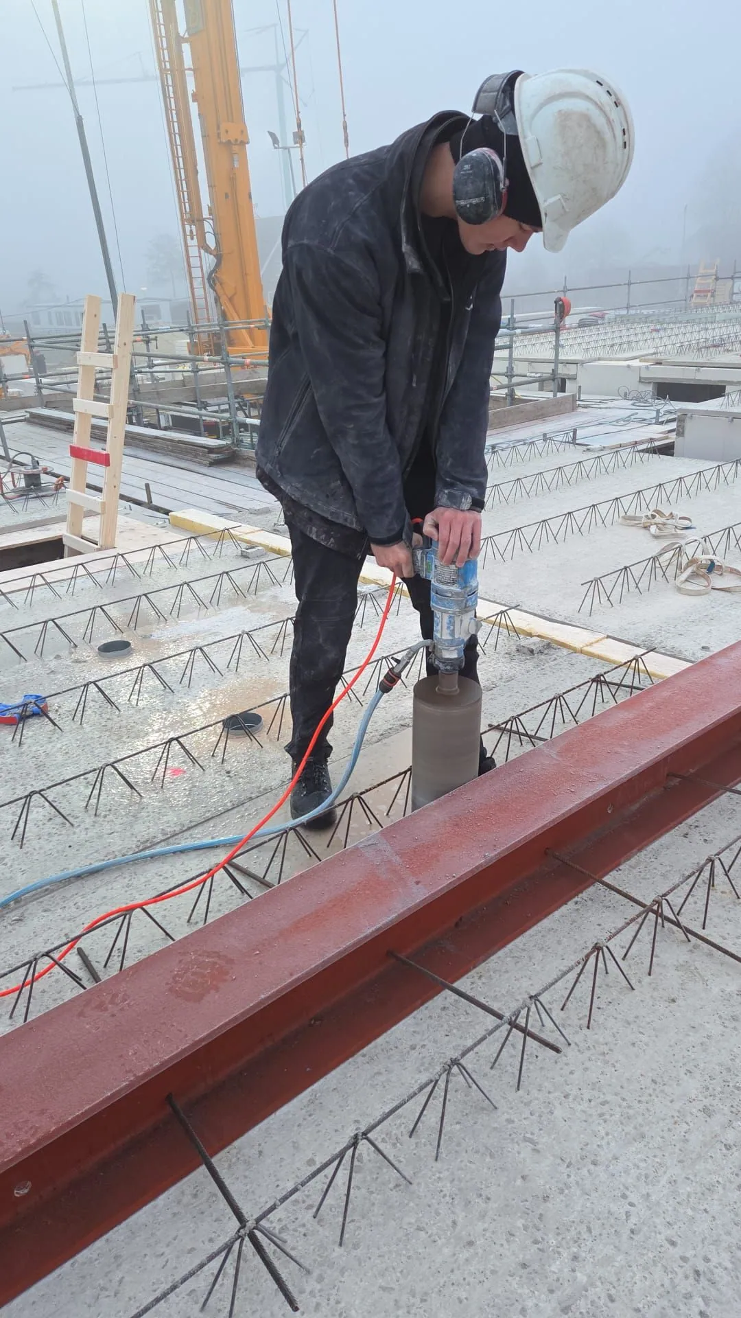 Medewerker maakt een verticale kernboring in een betonvloer op een bouwplaats