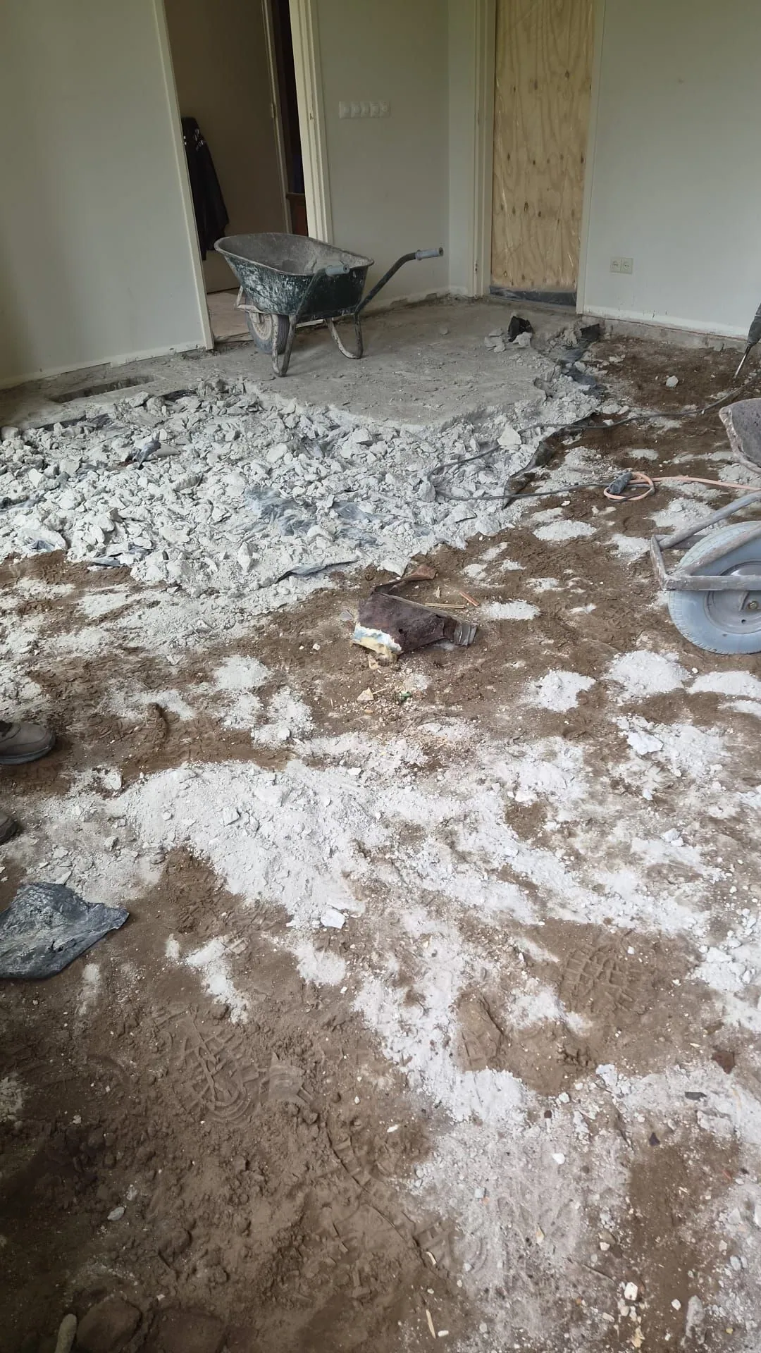 Binnenruimte met opgebroken vloermateriaal en een kruiwagen